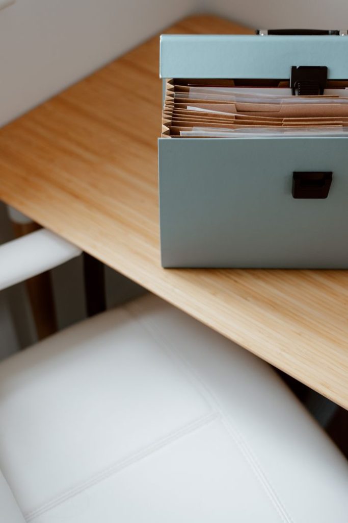 High angle of opened briefcase for documents with sorted documents in different compartments placed on empty wooden table